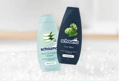 Schauma Shampoo für Männer, zwei Flaschen: Anti-Schuppen Classic mit Aloe Vera und For Men Shampoo mit Hopfenextrakt. Haarpflegeprodukte für spezifische Bedürfnisse, präsentiert vor einem verschwommenen Hintergrund.