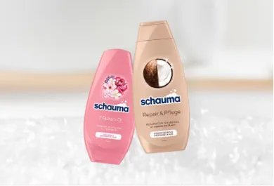 Schauma Shampoo, zwei Flaschen: 7-Blüten-Öl Shampoo für Glanz und Geschmeidigkeit sowie Repair & Pflege Shampoo mit Kokosnuss-Extrakt für strapaziertes Haar. Haarpflegeprodukte, präsentiert vor einem weichen, verschwommenen Hintergrund.