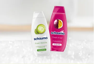 Schauma Shampoo, zwei Flaschen: Fresh Matcha Shampoo mit Matcha-Extrakt für fettiges Haar sowie Fresh it Up! Shampoo mit Passionsfrucht-Extrakt für frischen Duft und Pflege. Haarpflegeprodukte, präsentiert vor einem weichen, verschwommenen Hintergrund.