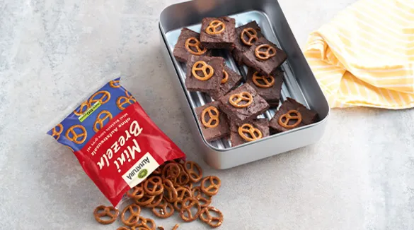 Brezel-Brownies in einer Edestahldose, daneben eine geöffnete Packung Alnatura Mini Brezeln