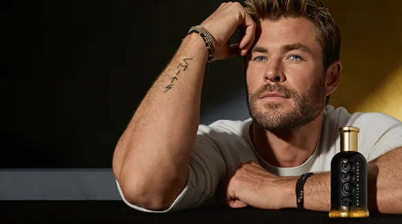 Der Schauspieler Chris Hemsworth, vor ihm eine Flasche BOSS Bottled Absolu