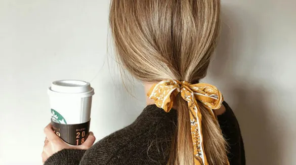 Frau-Rückenansicht-blondes-Haar-gelbe-Schleife-Kaffeebecher