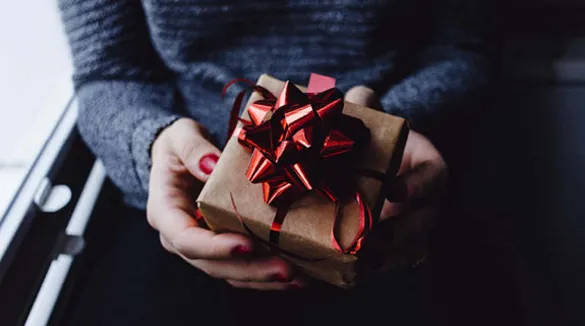 Frauenhände-roter-Nagellack-Geschenke-Geschenkpapier-mit-Weihnachtsbaumdruck-Zuckerstangen-rot-weißes-Geschenkband