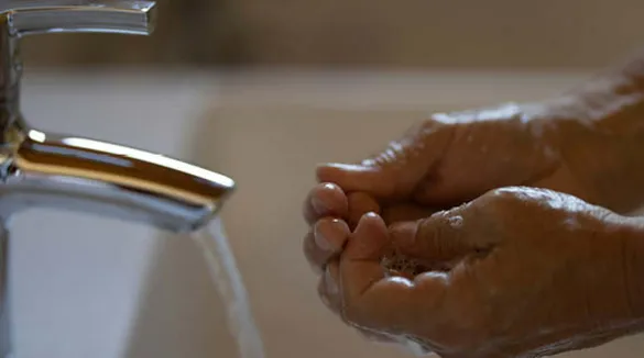 zwei-Männerhände-weißes-Waschbecken-Wasserhahn-Wasser-Händewaschen