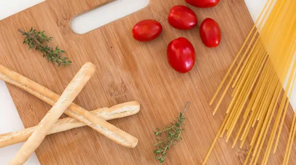 Holzschneidebrett-Grissini-Kirschtomaten-Spaghetti-Thymian