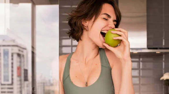 junge-Frau-beißt-in-grünen-Apfel-Küche