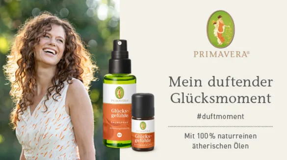 Links eine lachende Frau mit braunen gelockten Haaren im Grünen, rechts das Logo von Primavera, darunter "Mein duftender Glücksmoment"